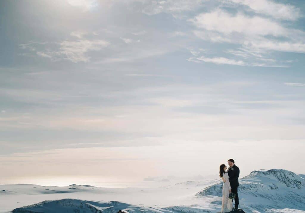 Bride and groom embrace on a snowy winter day in the south Icelandic countryside.