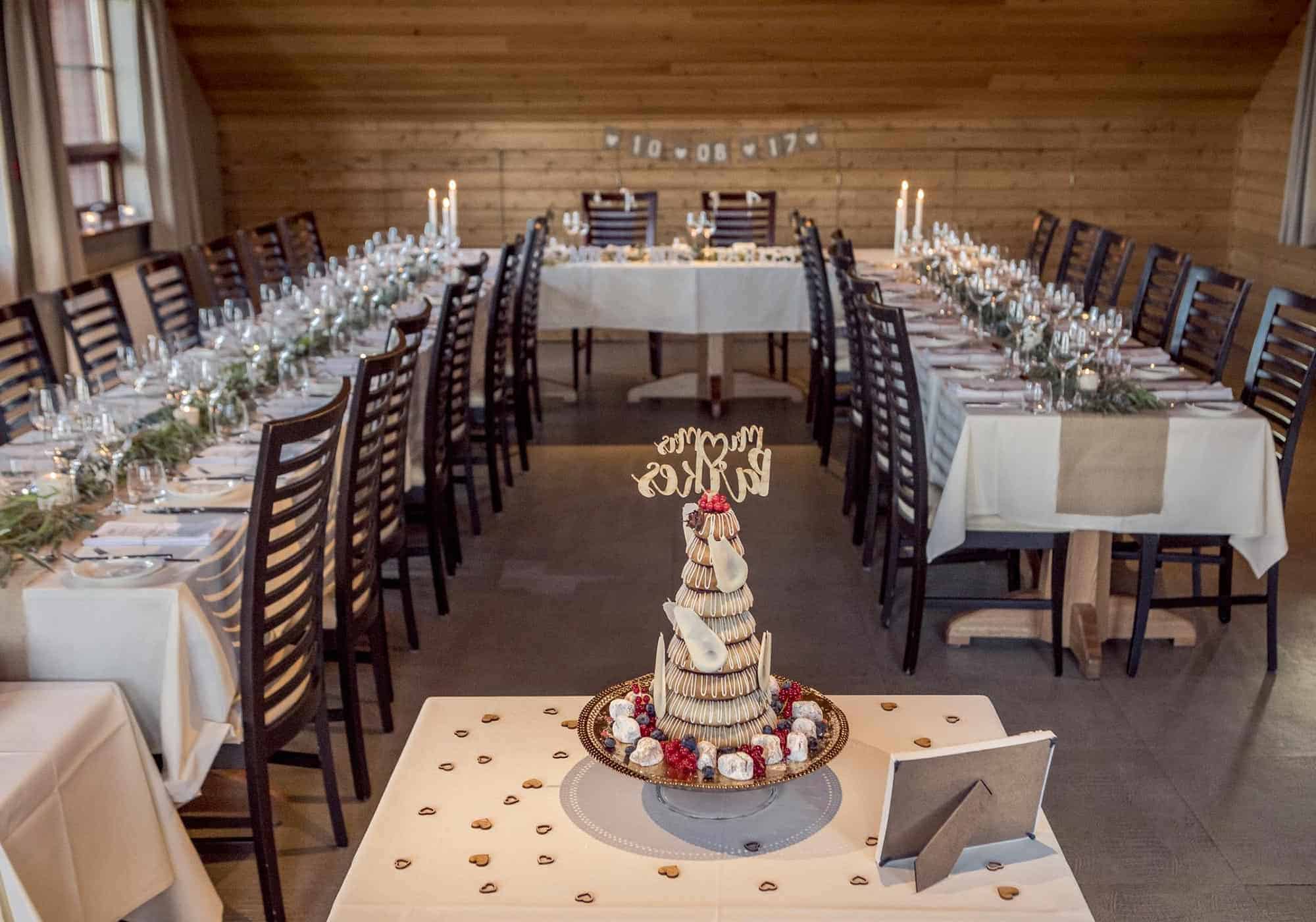 Tables set up in a u-shape in Hotel Rangá's River Hall with wedding decorations and a kransakaka wedding cake.