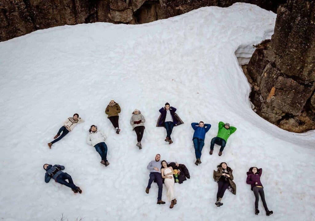A wedding party laying in snow, Icelandic destination wedding.