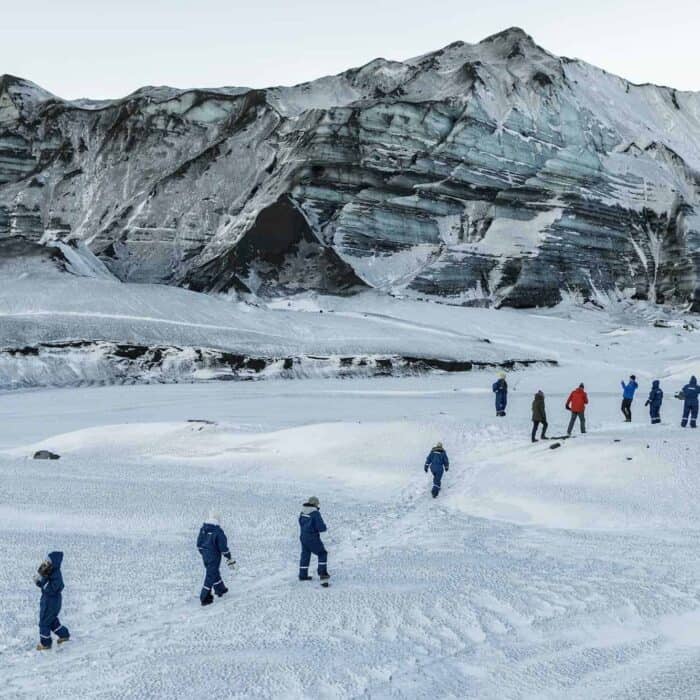 Hikers walking beside a glacier in south Iceland.