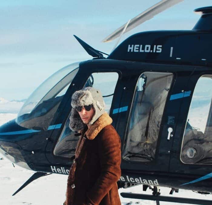 Lucas Raven stands in front of a helicopter on a snowy day in south Icealnd.