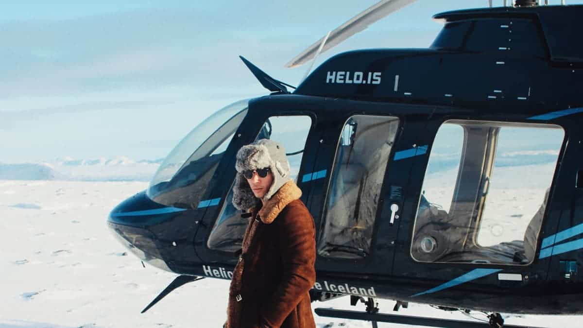 Lucas Raven stands in front of a helicopter on a snowy day in south Icealnd.