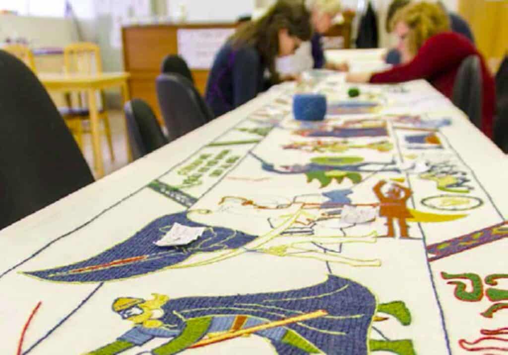 Women sewing a tapestry depicting Njáls Saga.