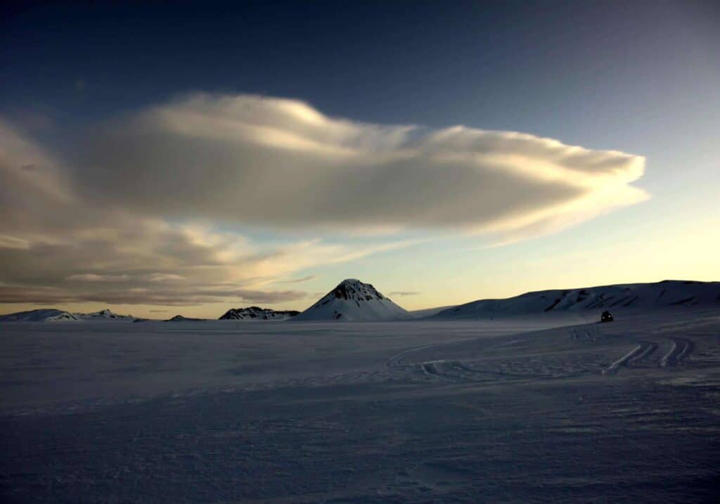 White puffy clouds drift over snow-covered mountains in south Iceland.