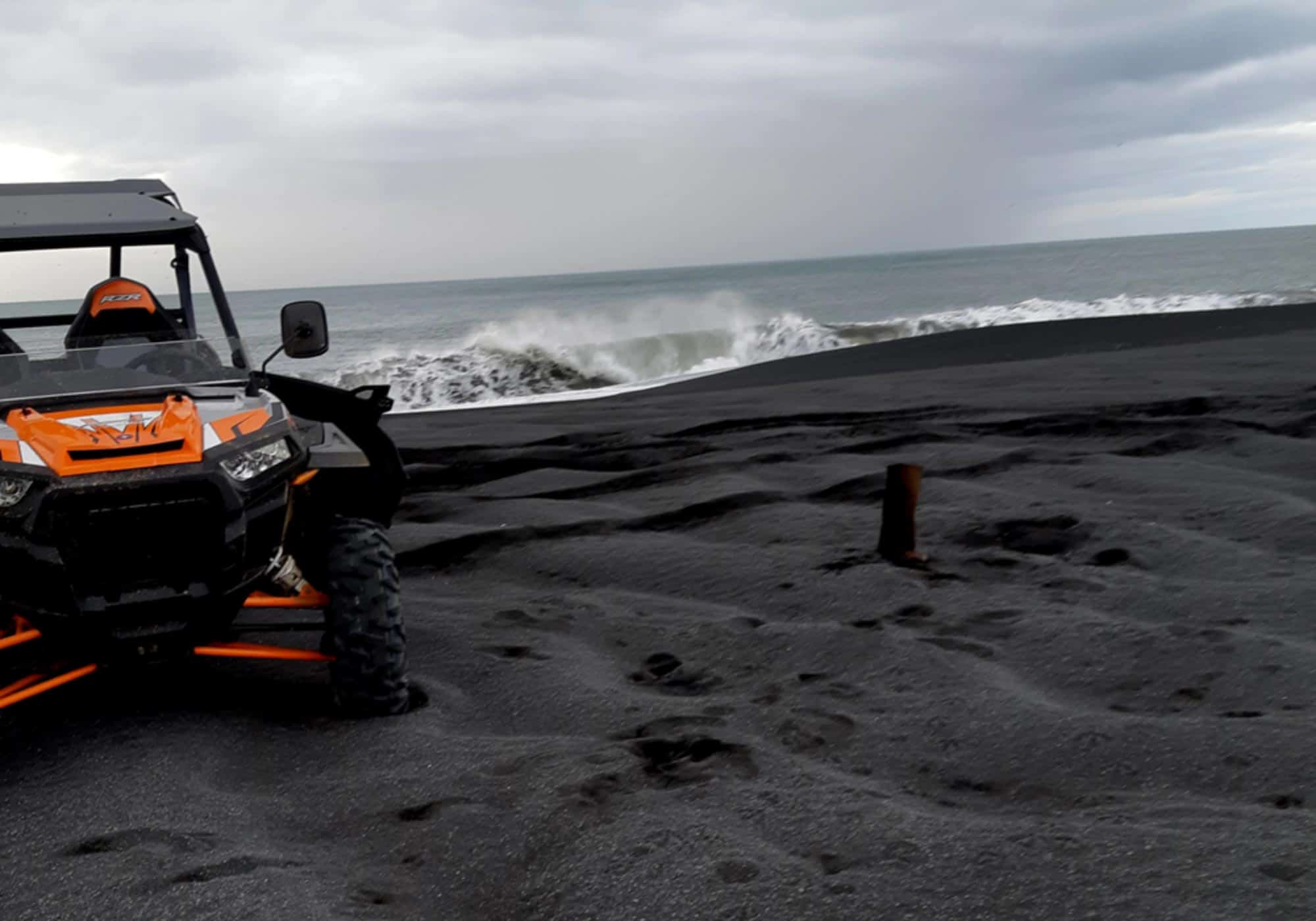Buggy on a black sand beach beside the ocean in south Iceland.