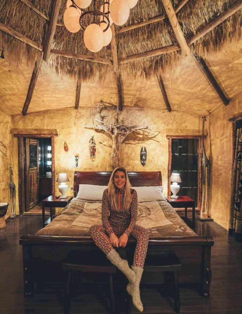 Woman sits on king bed in Hotel Rangá's Africa Suite. 