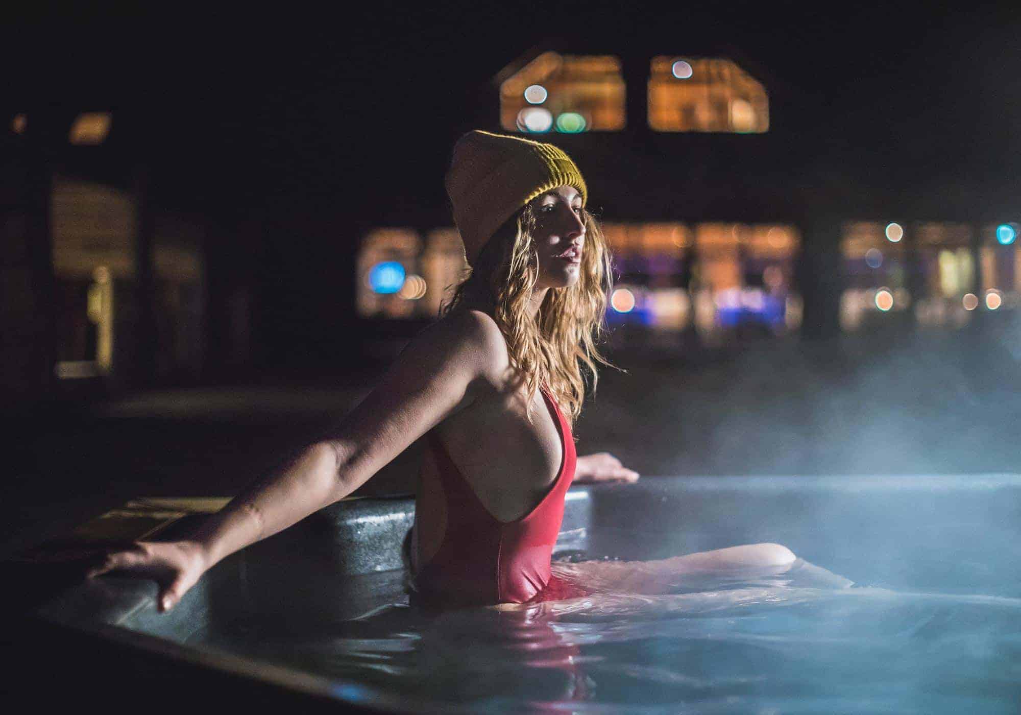 Woman soaks in a geothermal hot tub outside Hotel Rangá at night.