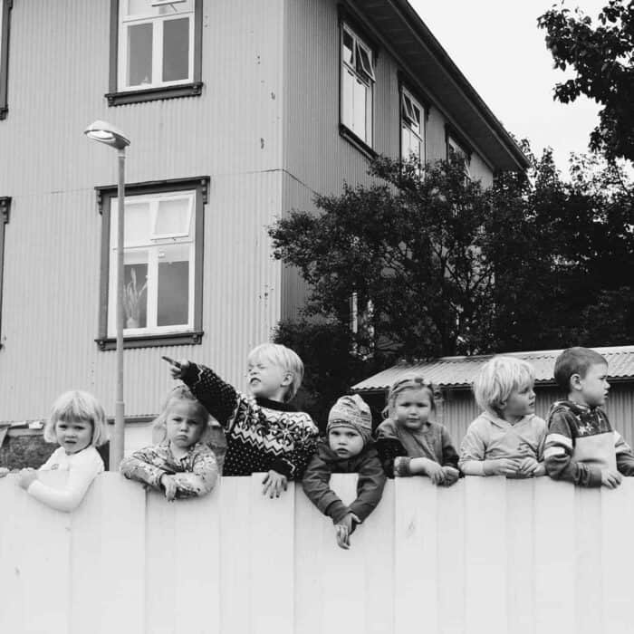 Icelandic children holding on to a white fence in Reykjavík.