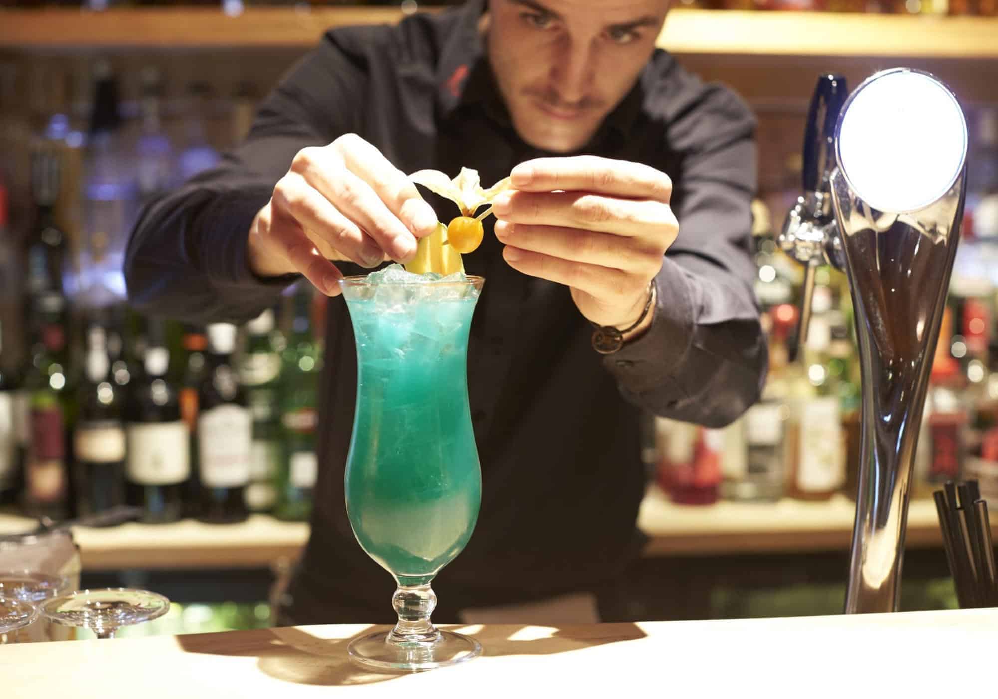 Hotel Rangá bartender adds garnish to bright blue cocktail at the Rangá Bar.