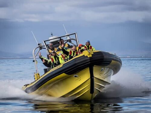 Passengers wave on a Rib Safari boat tour in the waters surrounding the Westman Islands.