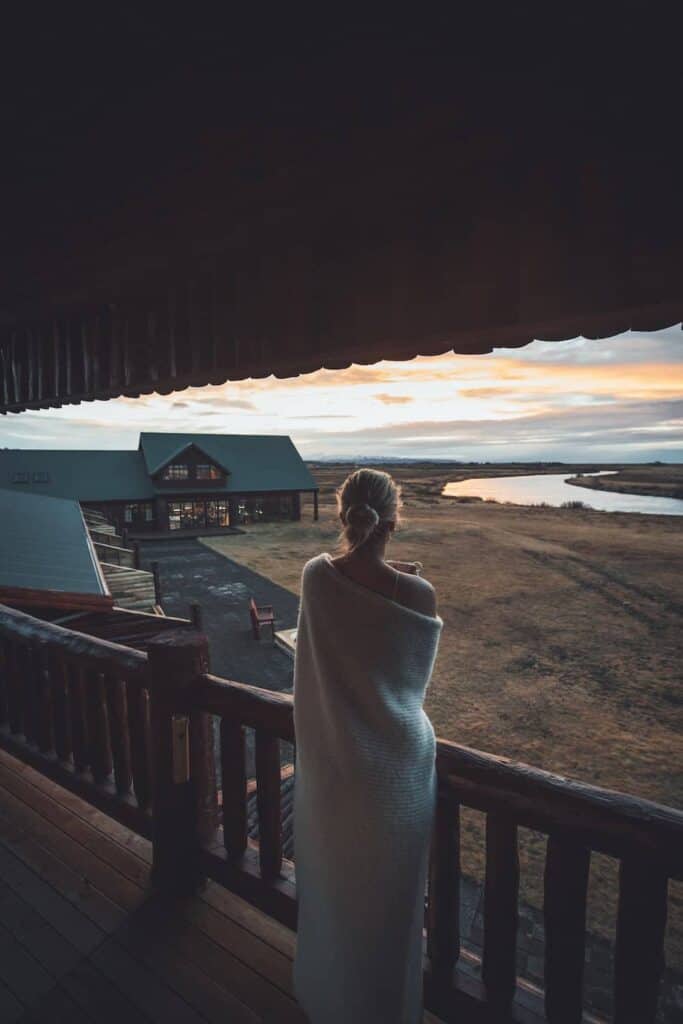 Woman stands on an outdoor balcony overlooking Hotel Rangá's exterior and the Rangá River.