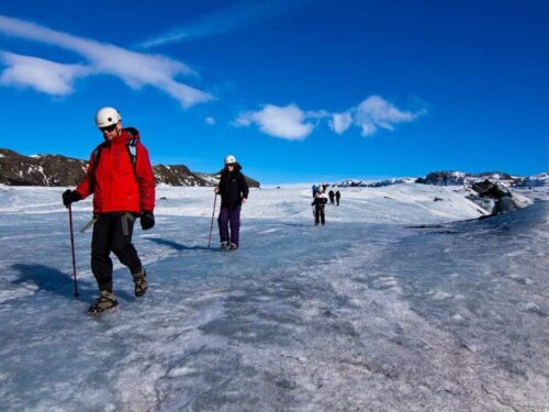 People hike across Solheimajökull glacier on glacier tours in Iceland.