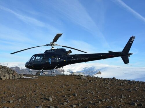 Helicopter sits atop mountain with view of Eyjafjallajökull glacier.