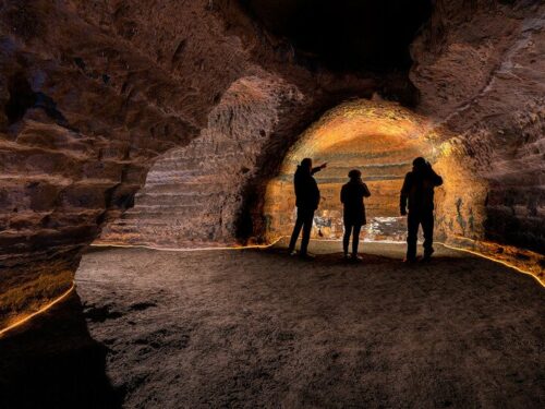 Silhouettes of three visitors standing inside the Caves of Hella in south Iceland.
