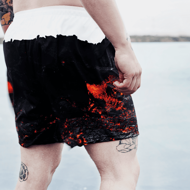 Man wearing Secret of Iceland swim trunks decorated with a volcanic lava design.