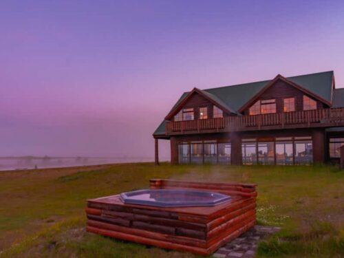 Exterior of Hotel Rangá under the midnight sun with geothermal hot tub in the foreground.