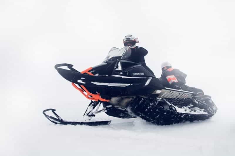 Black snowmobile drives across a snowy field in south Iceland.
