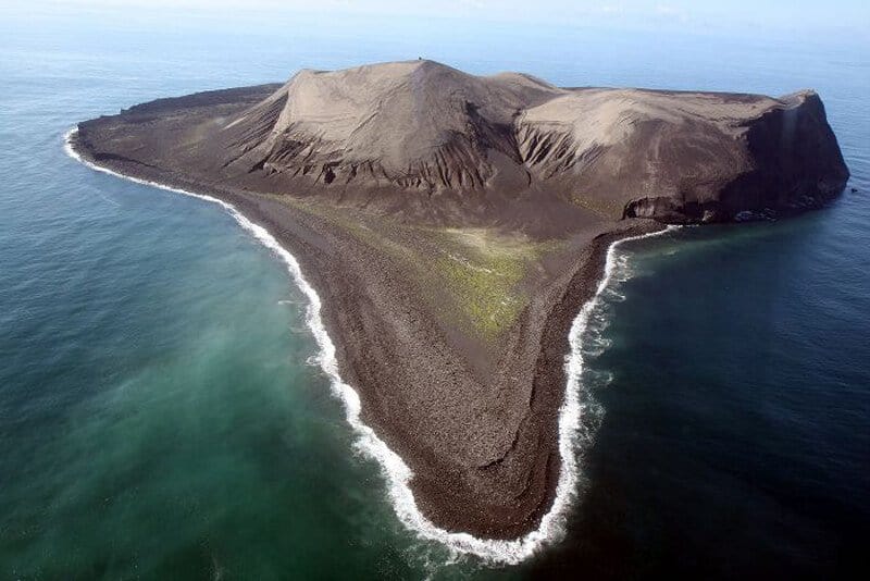 Surtsey volcanic island covered in black sand and surrounded by ocean waters.