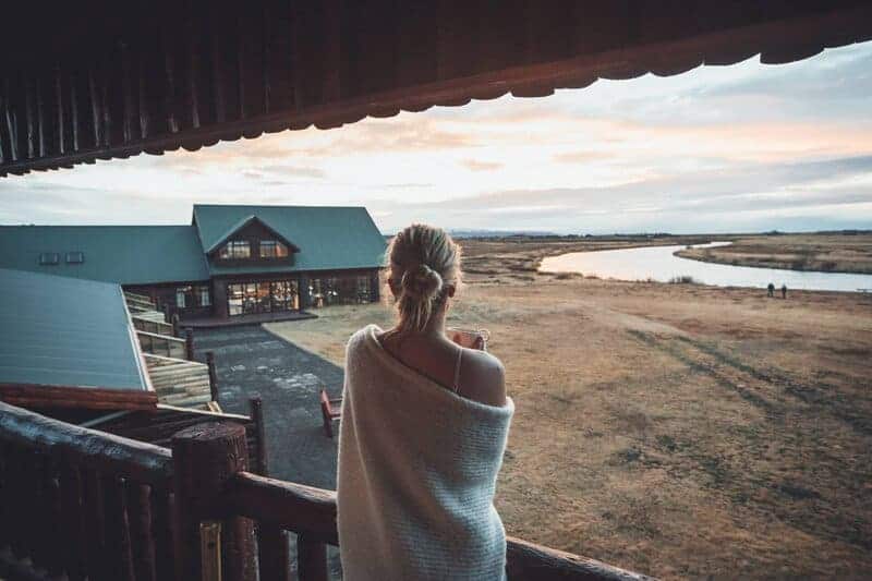 Woman stands on Hotel Rangá balcony overlooking the exterior of Hotel Rangá and the Rangá River.