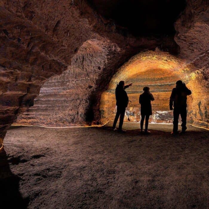 Three people stand silhouetted in the Caves of Hella in south Iceland.