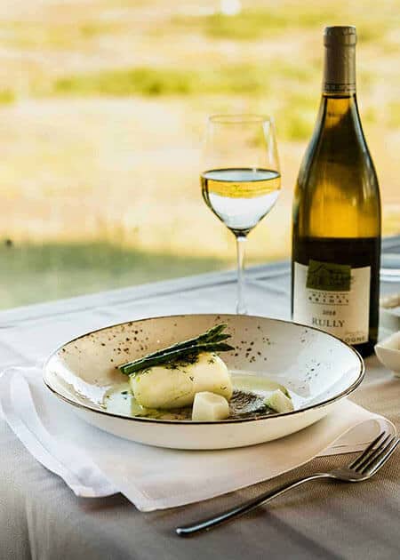 Plate of white fish and asparagus with a glass of white wine in the Rangá Restaurant.