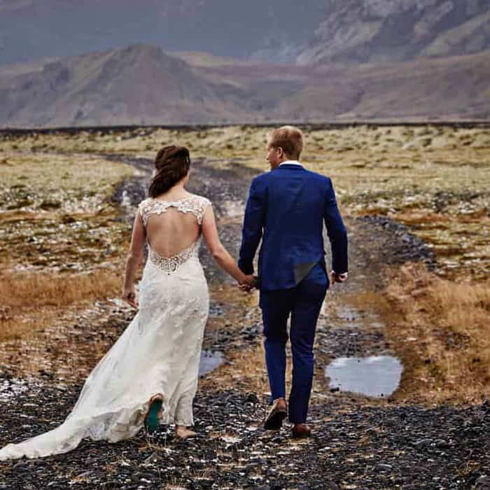 Hotel Rangá wedding couple holds hands in a field in south Iceland.