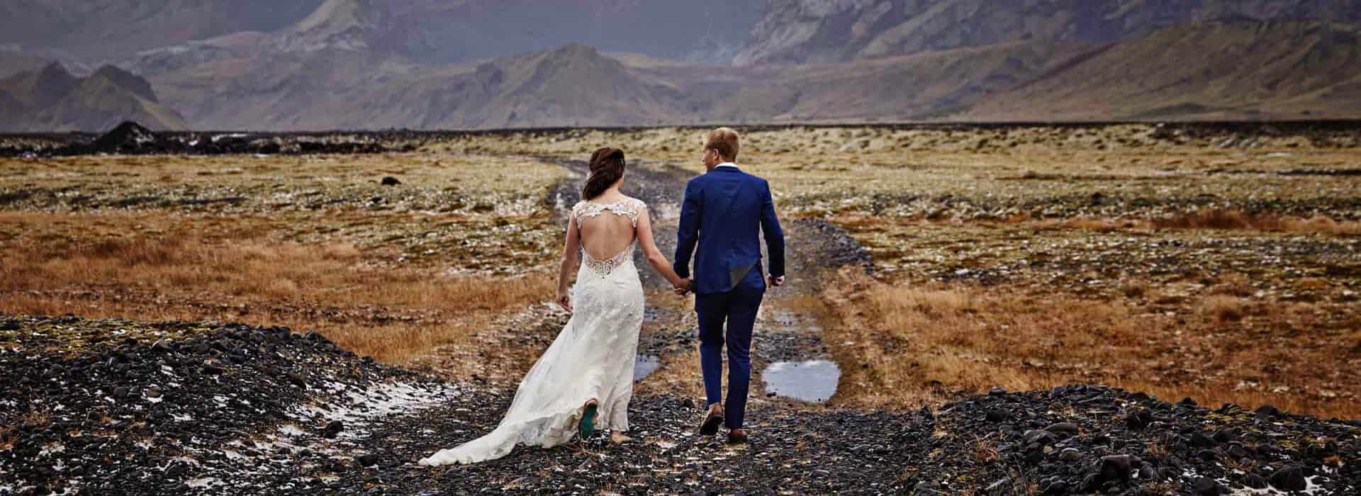 Hotel Rangá wedding couple holds hands in a field in south Iceland.