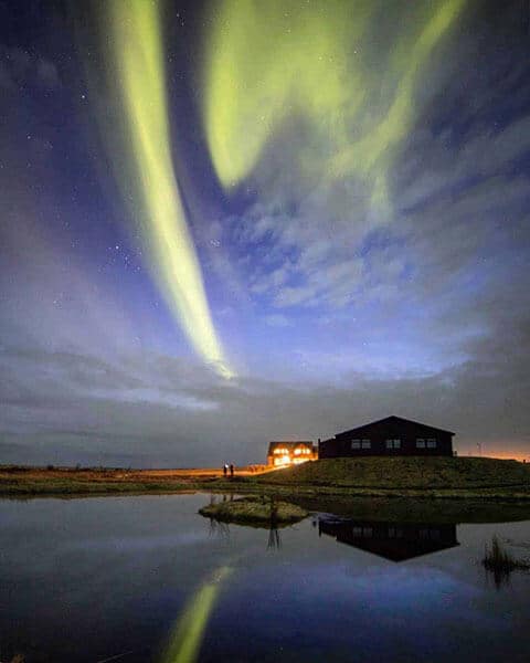 Green northern lights in a cloud sky over Hotel Rangá in south Iceland.