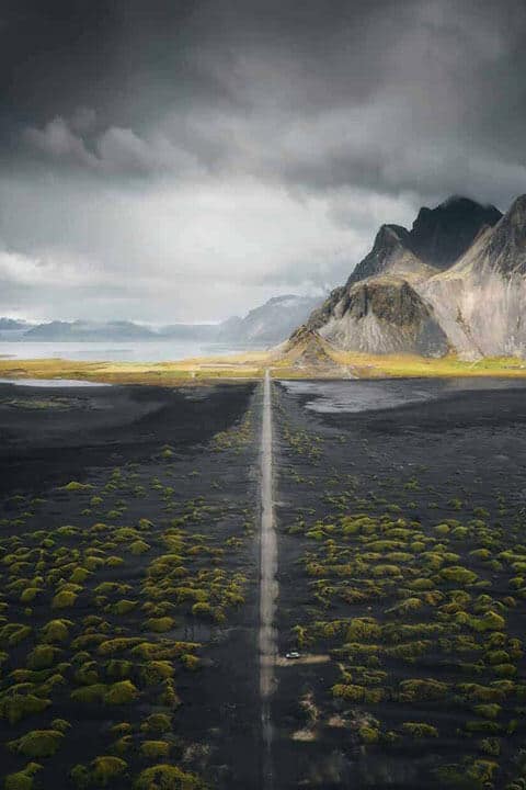 Country road in south Iceland with view of mountains and ocean in background.