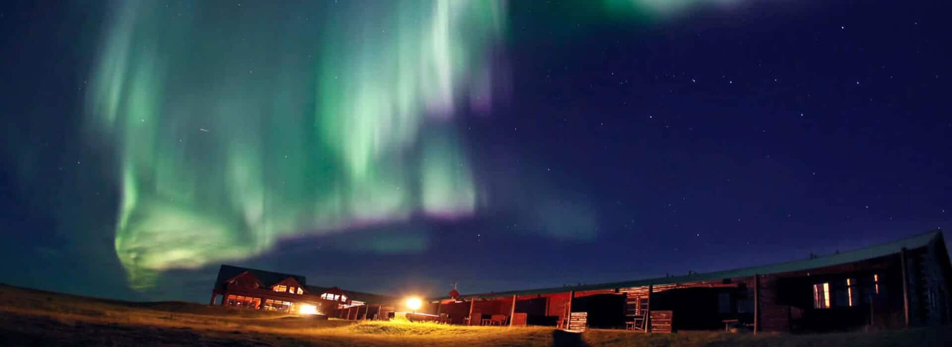 Green and purple northern lights in the sky over Hotel Rangá luxury hotel in south Iceland.