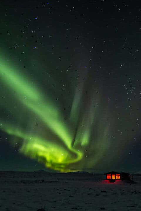 Swirling green northern lights in a starry sky over the Hotel Rangá Observatory.