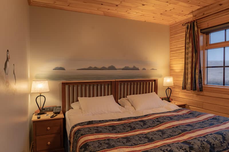 View of a standard room in Hotel Rangá including a King bed, two nightstands a window and a wall mural.