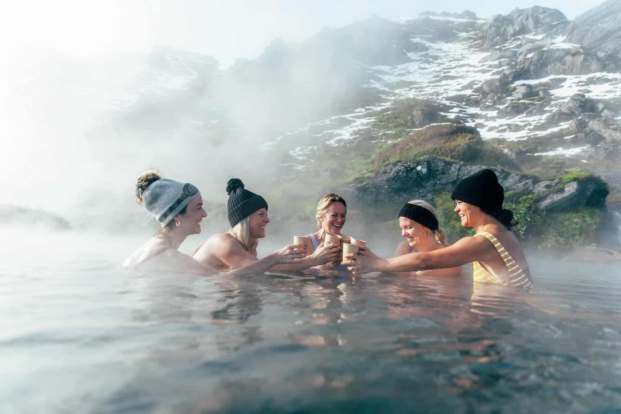 A group of women clink glasses in the famouns Landmannalaugar hot spring on the edge of the highlands.