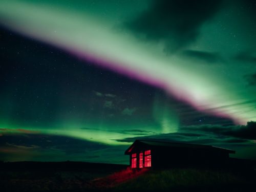 A pink and green band of northern lights stretches out across the sky over the Hotel Rangá Observatory.