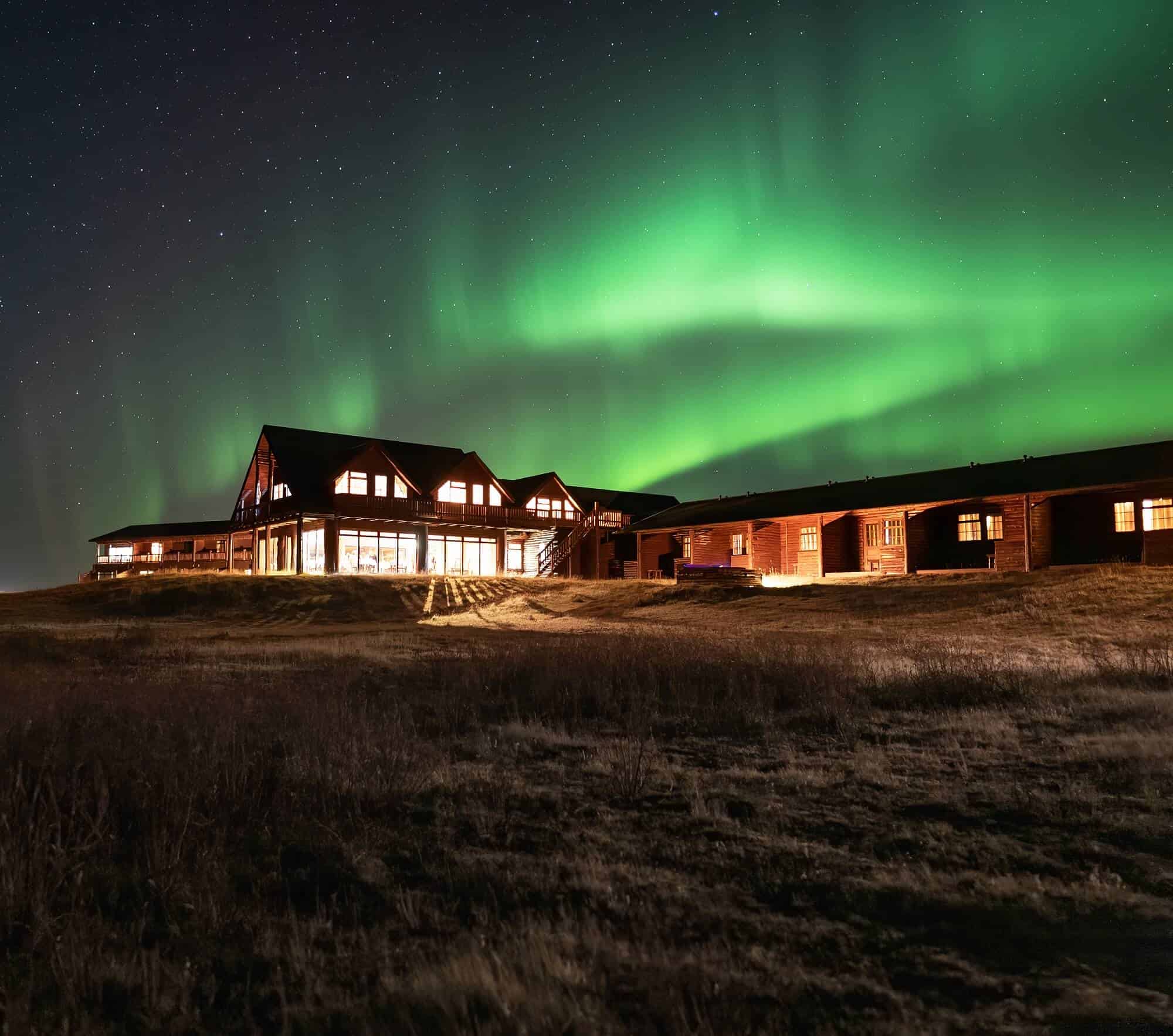 Green northern lights glow above Hotel Rangá luxury hotel in south Iceland.