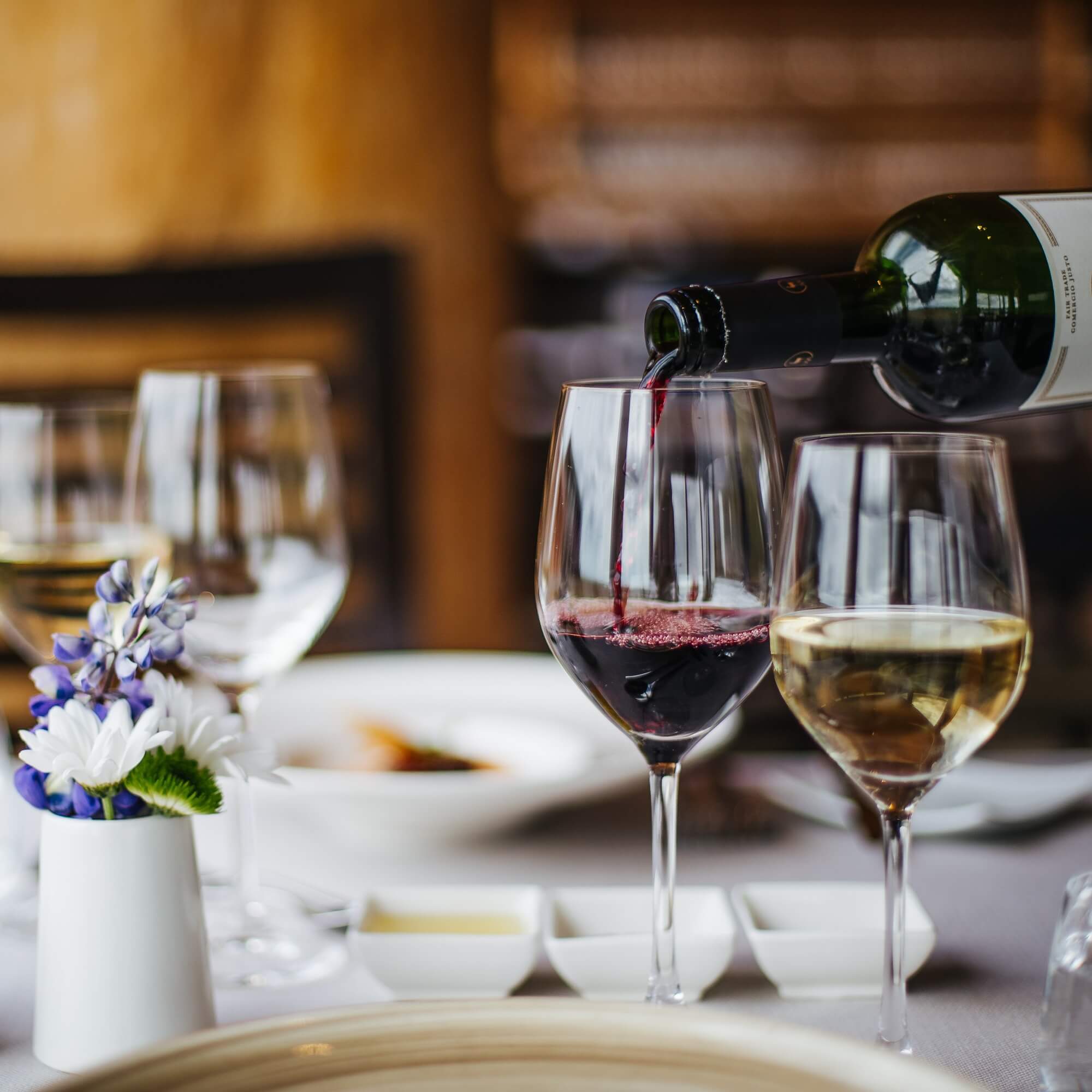 A glass of red and white wine beside a vase of lupine at the luxury Rangá Restaurant.
