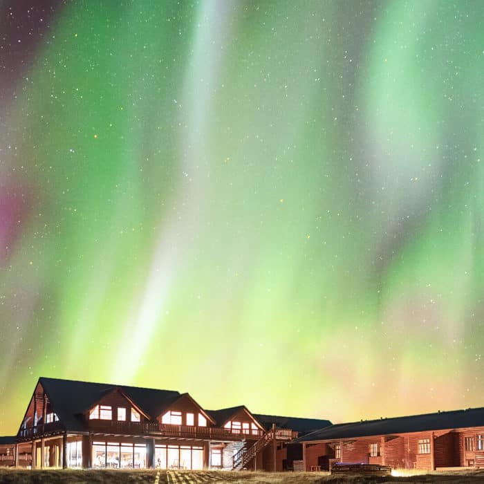 Green and pink northern lights shimmer above Hotel Rangá luxury hotel in south Iceland.