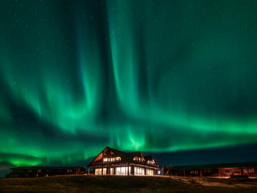 Green northern lights dance above Hotel Rangá luxury hotel in south Iceland.
