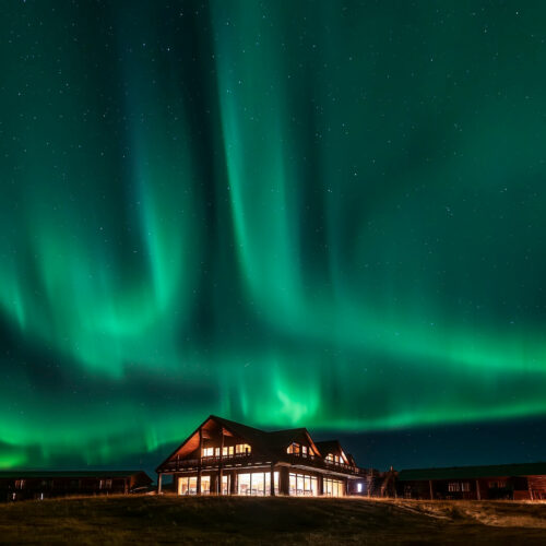 Green northern lights dance above Hotel Rangá luxury hotel in south Iceland.