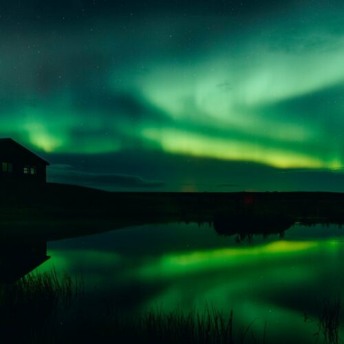 Green northern lights reflected on a pond at Hotel Rangá in south Iceland.