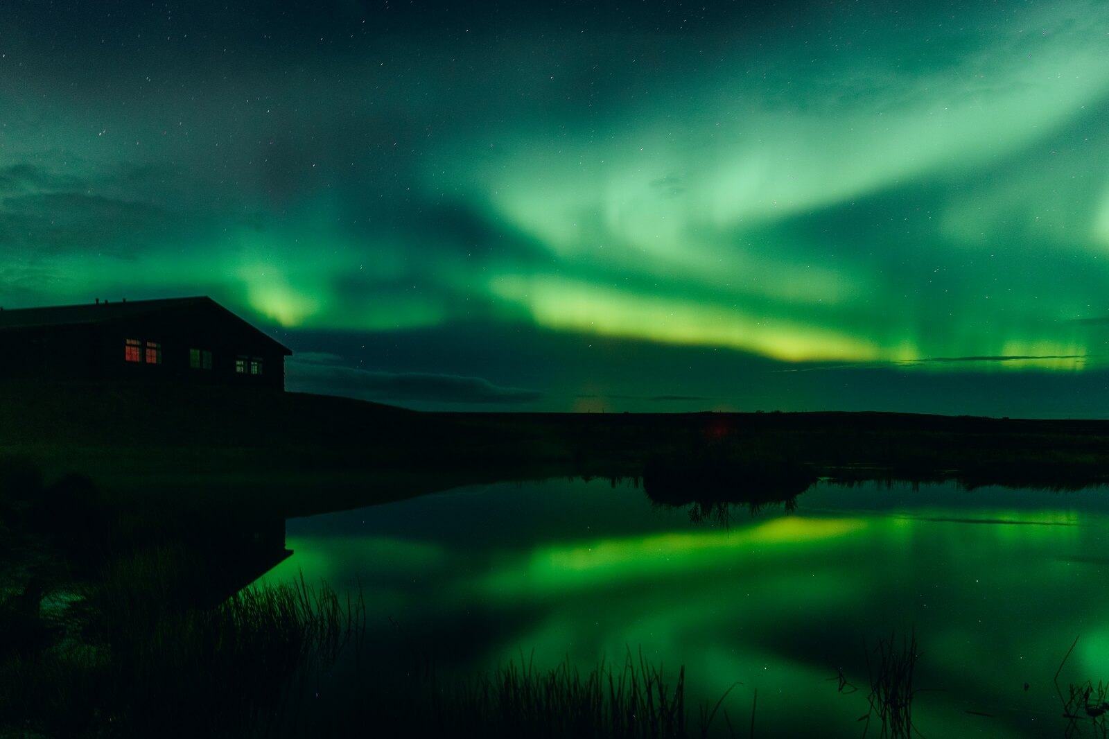 Green northern lights reflected on a pond at Hotel Rangá in south Iceland.