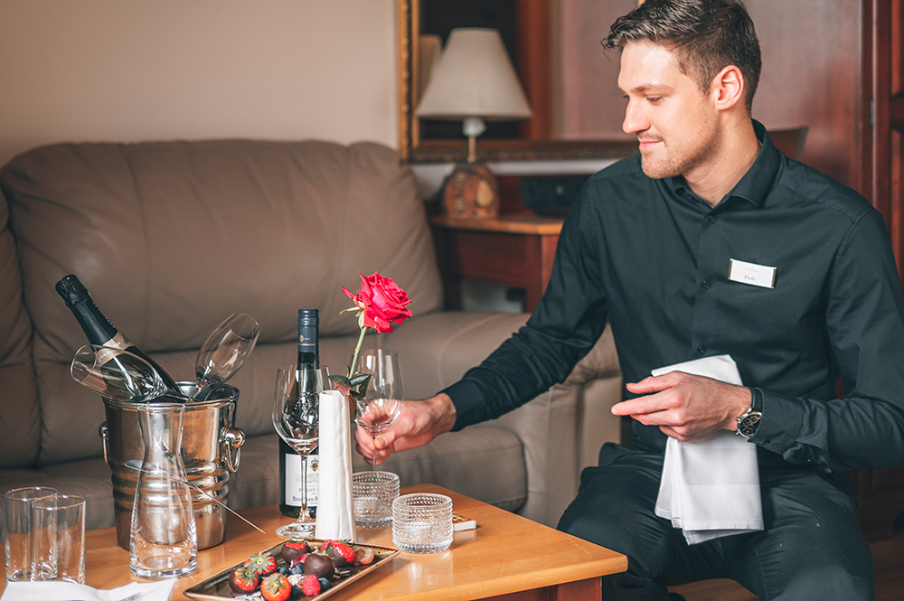 Waiter putting out a romantic setting of champagne and chocolate covered strawberries in one of Hotel Rangá's rooms.