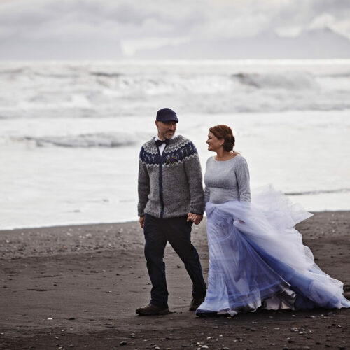 Stacey Nelson and Jerry Stover walk across a black sand beach in south Iceland in front of the Atlantic Ocean.
