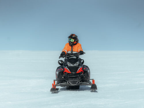 A woman rides a snowmobile on the Eyjafjallajökull glacier.