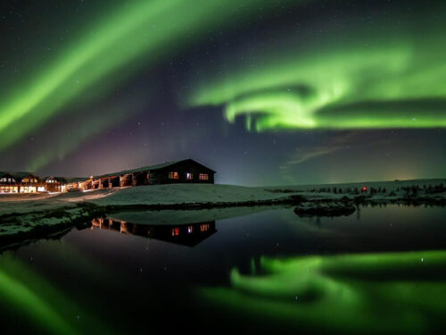 The northern lights glow green over Hotel Rangá on a snow winter night.