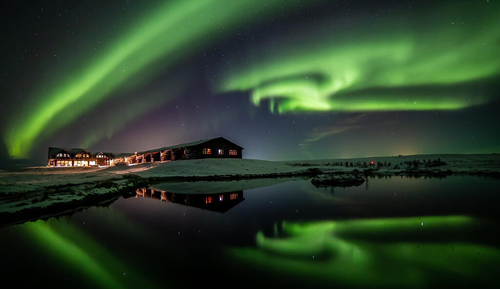The northern lights glow green over Hotel Rangá on a snow winter night.