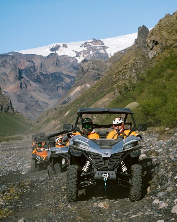 Riders in buggies on a group tour in Iceland with snow-covered mountains in the background.