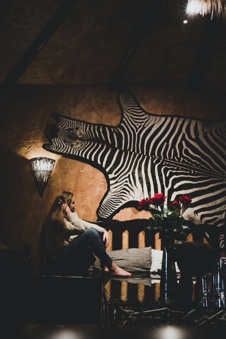 Woman sits in the Hotel Rangá Africa suite underneath a zebra skin wall hanging.