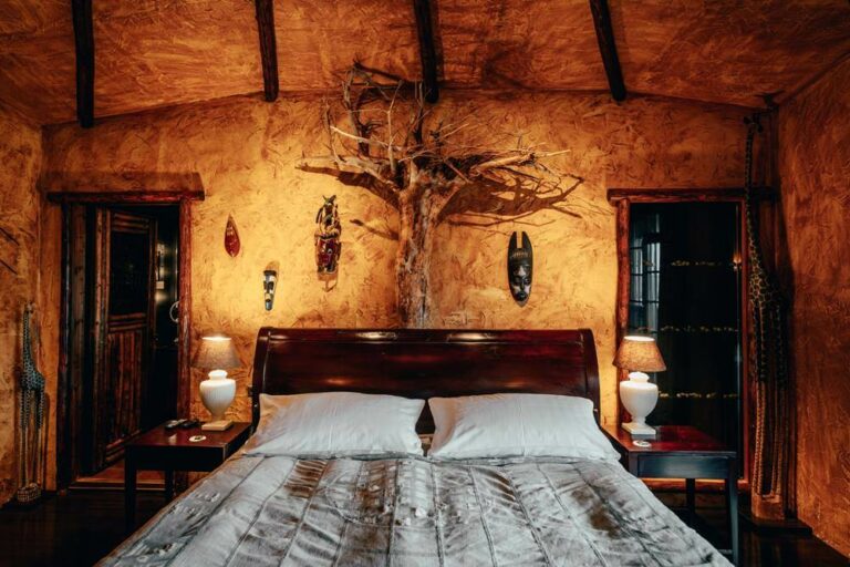 Hotel Rangá Africa Master Suite featuring a thatched roof and traditional artwork including a tree hanging above the King bed.
