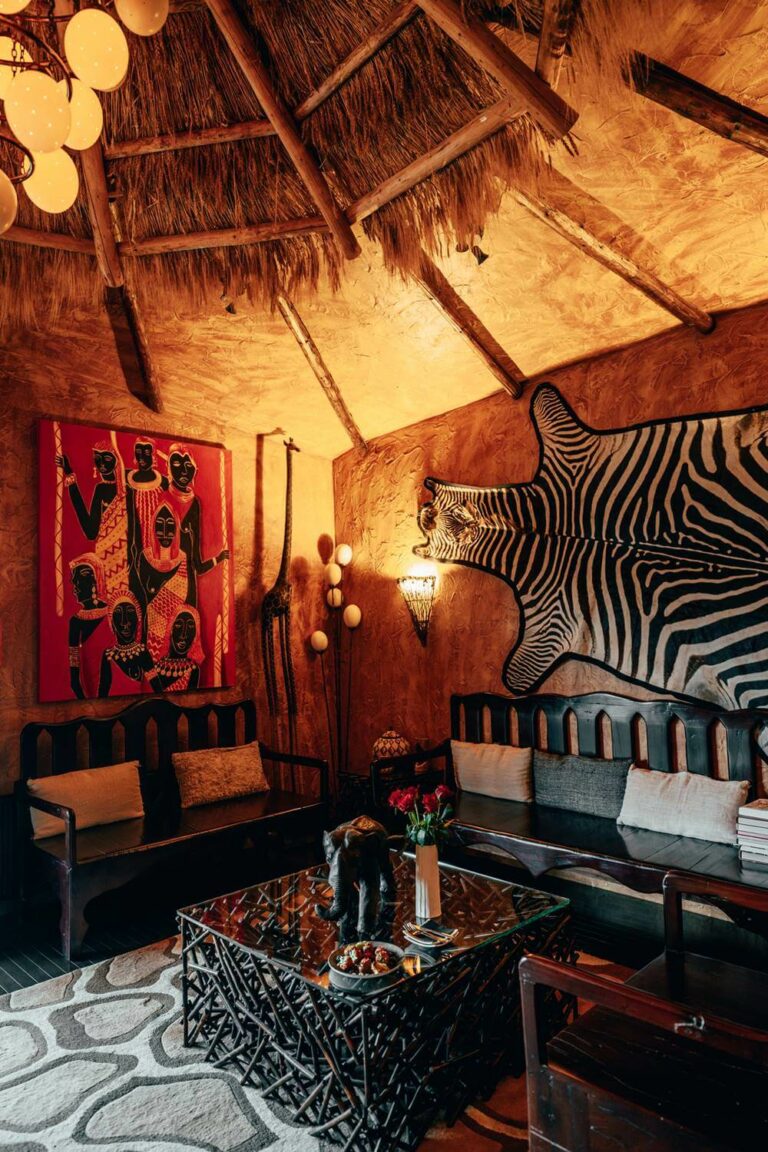 Hotel Rangá's Africa Suite decorated with a straw ceiling, ostrich egg chandelier, zebra skin wall hanging, painting of Africans in traditional dress and wooden furniture.